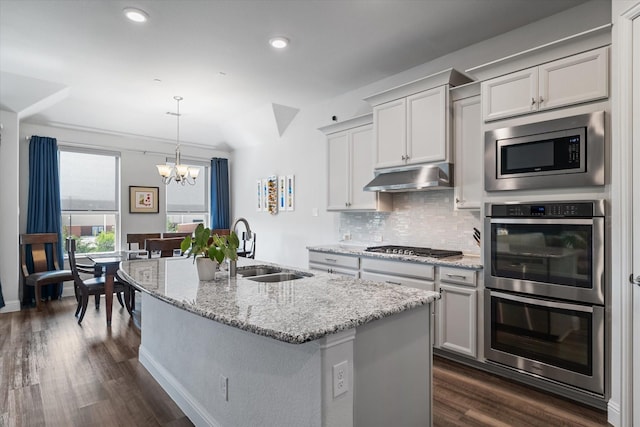 5542 Yellowstone Rd, The Colony, TX 75056 - kitchen featuring under cabinet range hood, stainless steel appliances, tasteful backsplash, a chandelier, and dark wood-type flooring