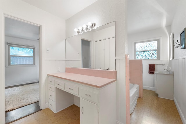 2137 Lenamon St, Waco, TX 76710 - bathroom featuring wainscoting, wood finished floors, vanity, and a bath