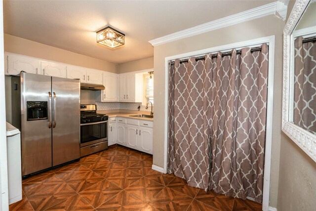 97 Wade St, Nocona, TX 76255 - kitchen featuring appliances with stainless steel finishes, under cabinet range hood, white cabinets, a sink, and ornamental molding