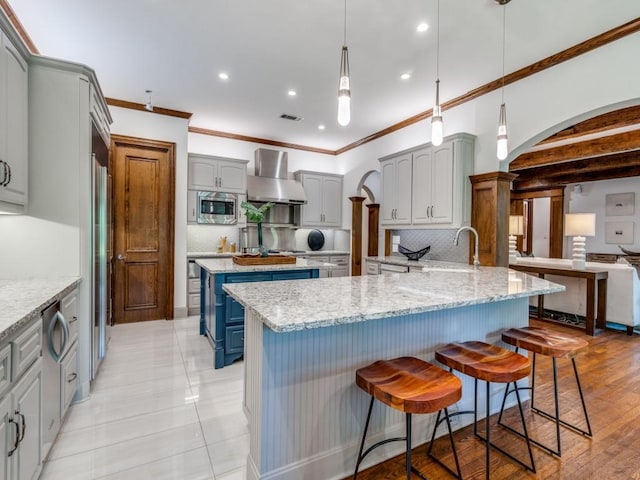 6302 Waggoner Dr, Dallas, TX 75230 - kitchen with wall chimney exhaust hood, stainless steel microwave, a sink, arched walkways, and decorative backsplash