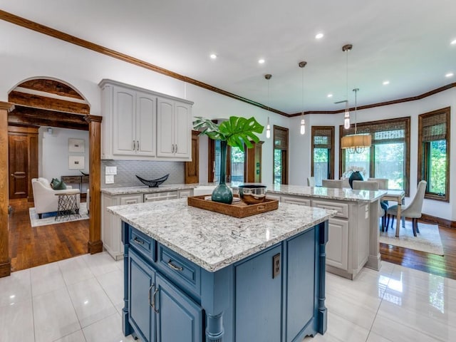 6302 Waggoner Dr, Dallas, TX 75230 - kitchen with a center island, light tile patterned flooring, recessed lighting, blue cabinetry, and light stone countertops