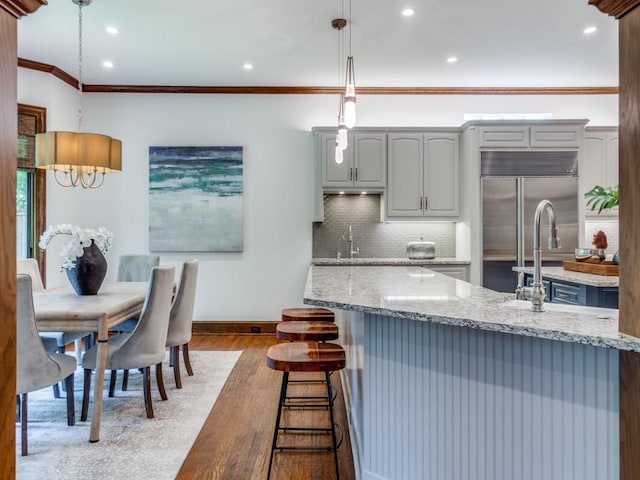 6302 Waggoner Dr, Dallas, TX 75230 - kitchen featuring stainless steel built in fridge, baseboards, wood finished floors, a kitchen breakfast bar, and light stone counters