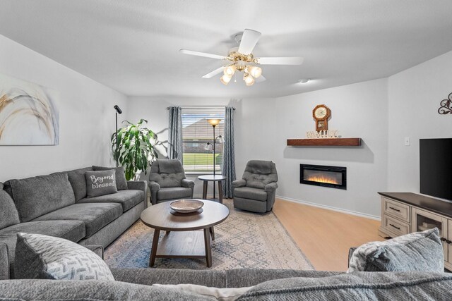 1930 Copper Ridge Cir, Rockwall, TX 75032 - living room featuring wood finished floors, a glass covered fireplace, a ceiling fan, and baseboards