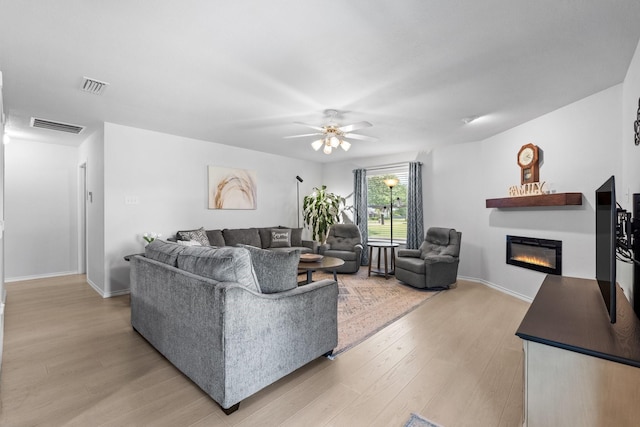 1930 Copper Ridge Cir, Rockwall, TX 75032 - living room featuring light wood-style flooring, a glass covered fireplace, ceiling fan, and baseboards