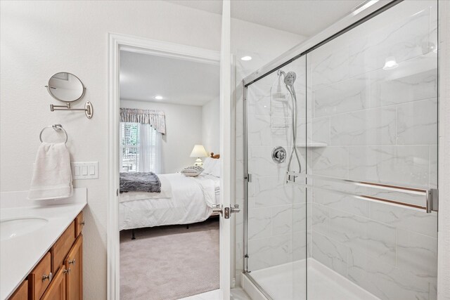 ensuite bathroom with a marble finish shower, vanity, and recessed lighting