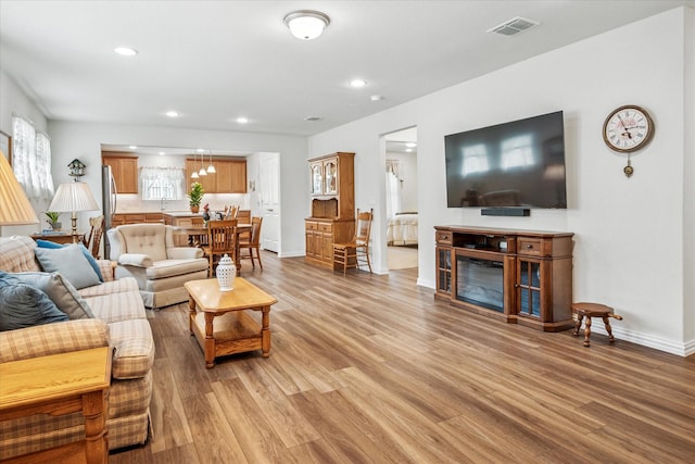 living area with light wood-type flooring, baseboards, and recessed lighting