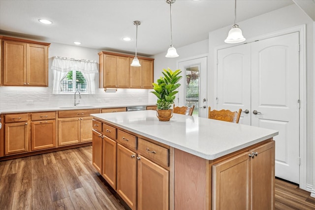 kitchen with a sink, dark wood-type flooring, decorative backsplash, light countertops, and a center island