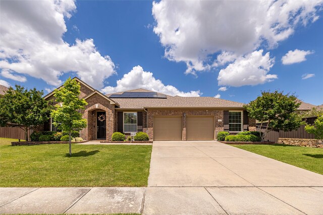 view of front of home with brick siding, an attached garage, solar panels, concrete driveway, and a shingled roof
