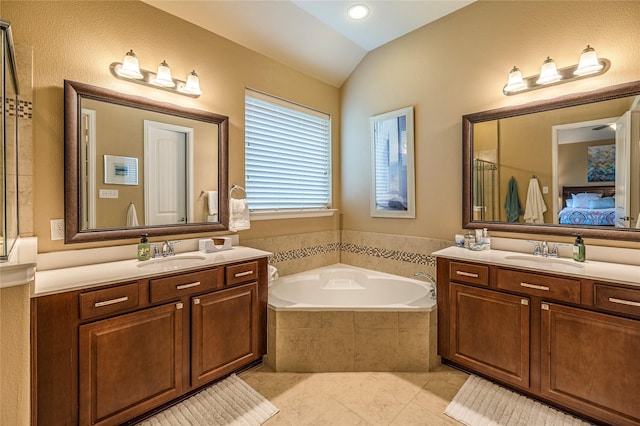 ensuite bathroom with two vanities, tile patterned floors, lofted ceiling, and a garden tub