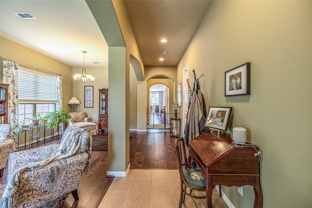 foyer featuring arched walkways, a chandelier, recessed lighting, baseboards, and wood finished floors