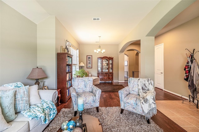 living room with arched walkways, wood finished floors, a chandelier, and baseboards