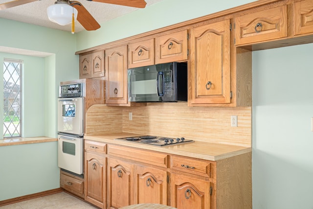 kitchen featuring black microwave, stainless steel electric stovetop, white double oven, light countertops, and backsplash