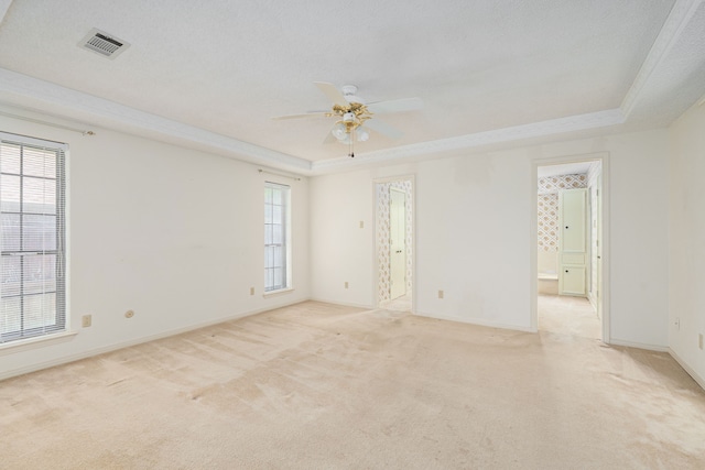 spare room featuring a tray ceiling, a ceiling fan, light carpet, and baseboards