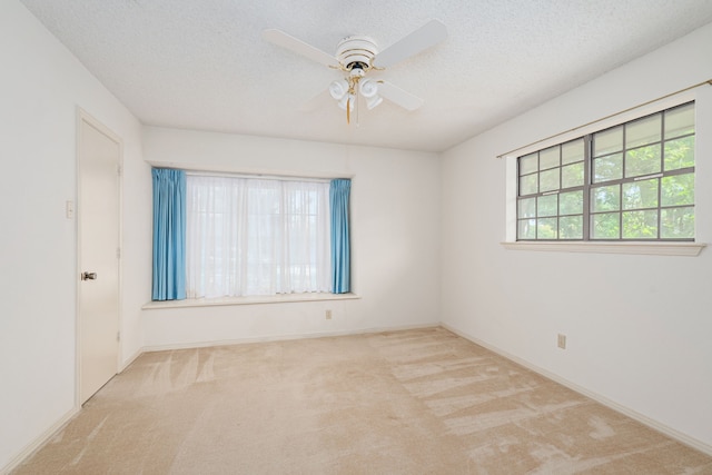 carpeted empty room featuring a ceiling fan, a textured ceiling, and baseboards