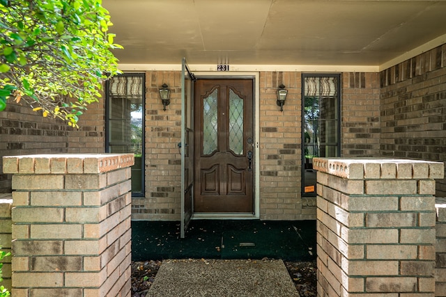 doorway to property with brick siding and a porch