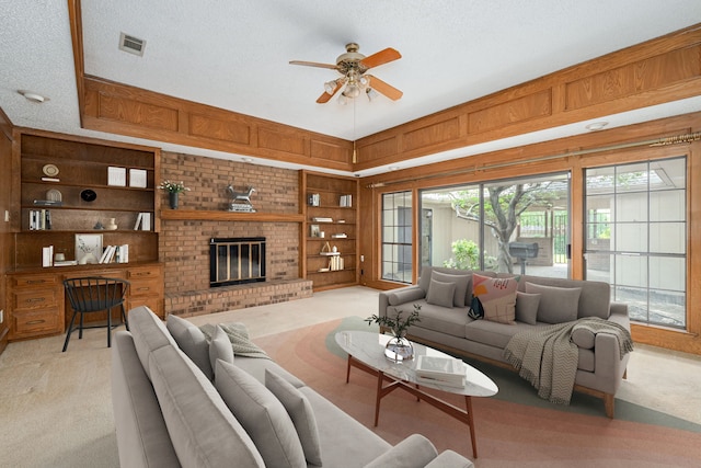 living room featuring light colored carpet, a ceiling fan, wooden walls, a textured ceiling, and a fireplace
