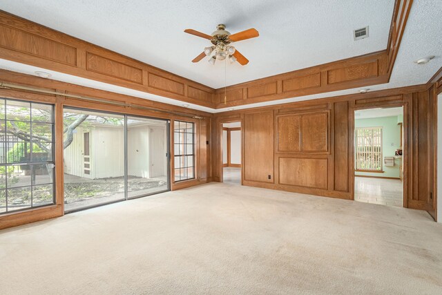 spare room with carpet flooring, a ceiling fan, and wooden walls