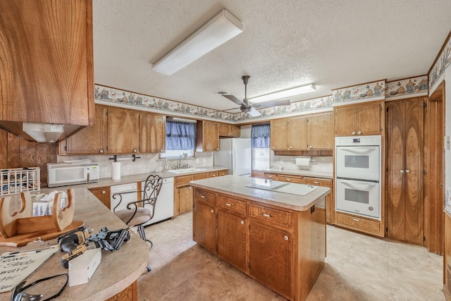 9820 County Road 514, Alvarado, TX 76009 - kitchen featuring white appliances, a sink, a textured ceiling, light countertops, and a kitchen island