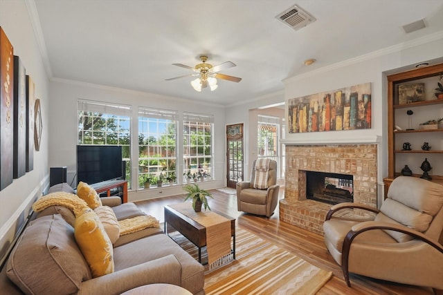 living area with light wood-type flooring, plenty of natural light, ornamental molding, and a brick fireplace