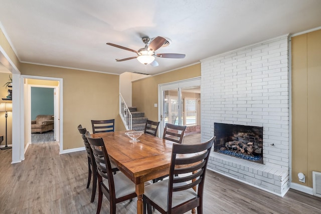 1809 Esquire Pl, Grand Prairie, TX 75050 - dining space with stairs, a ceiling fan, wood finished floors, a brick fireplace, and ornamental molding