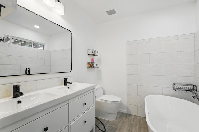 6801 Sweetwater Dr, Plano, TX 75023 - full bathroom with a freestanding bath, wood finished floors, double vanity, and toilet