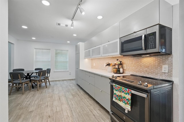 6801 Sweetwater Dr, Plano, TX 75023 - kitchen featuring stainless steel appliances, white cabinets, tasteful backsplash, light wood-style floors, and recessed lighting