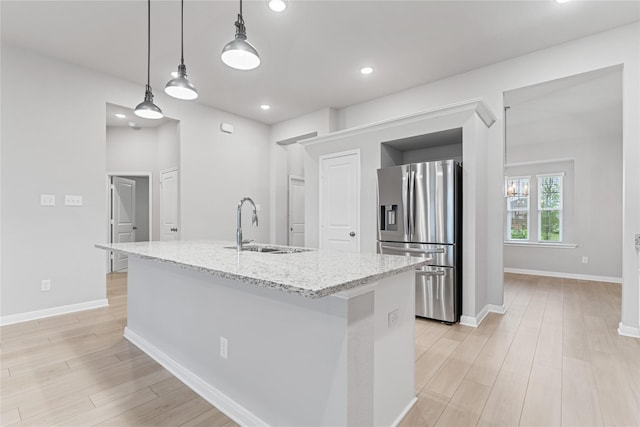 3625 Beutel Rd, Waco, TX 76655 - kitchen with stainless steel fridge, a sink, light wood-type flooring, light stone counters, and a kitchen island with sink