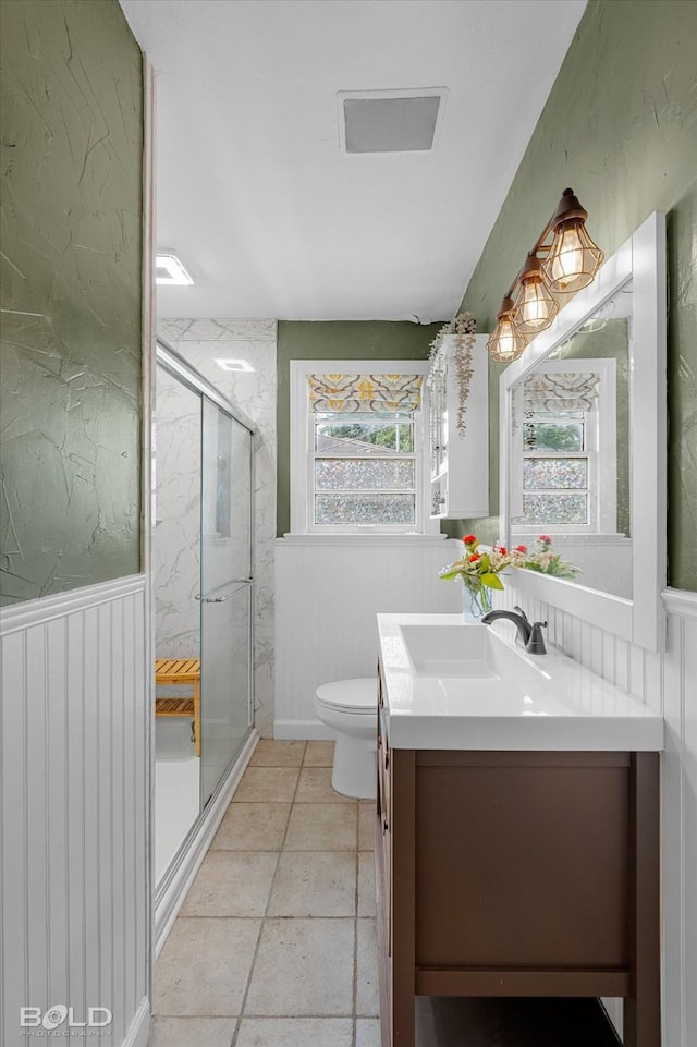 bathroom with a marble finish shower, vanity, toilet, and a wainscoted wall