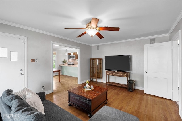 living area featuring wood finished floors, ceiling fan, crown molding, and baseboards