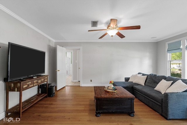 living area featuring light wood-style floors, ceiling fan, crown molding, and baseboards