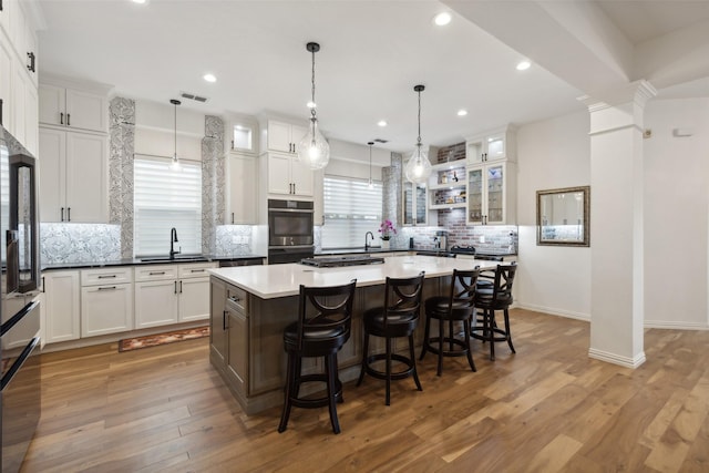 731 Bradford St, Lantana, TX 76226 - kitchen featuring a sink, double oven, backsplash, a breakfast bar area, and white cabinets