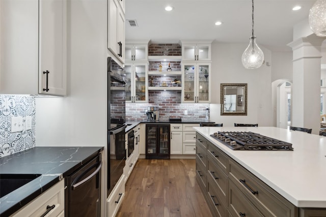 731 Bradford St, Lantana, TX 76226 - kitchen featuring beverage cooler, black appliances, arched walkways, wood-type flooring, and decorative backsplash