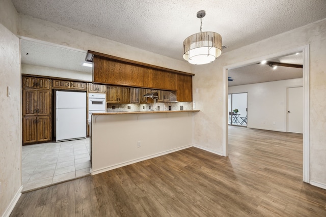 731 N Horne St, Duncanville, TX 75116 - kitchen featuring white appliances, wood finished floors, a peninsula, a textured ceiling, and under cabinet range hood