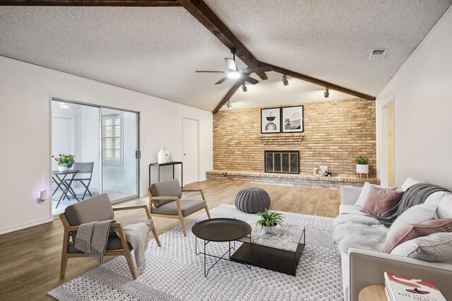 731 N Horne St, Duncanville, TX 75116 - living area featuring brick wall, wood finished floors, a textured ceiling, a brick fireplace, and ceiling fan