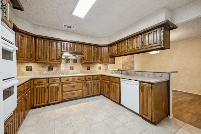 731 N Horne St, Duncanville, TX 75116 - kitchen with white appliances, under cabinet range hood, a textured ceiling, backsplash, and light countertops