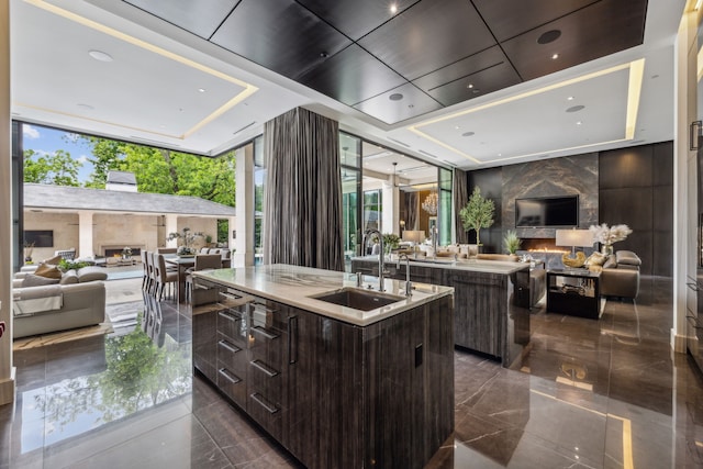 5214 Royal Ln, Dallas, TX 75229 - kitchen with open floor plan, a center island with sink, modern cabinets, a sink, and dark brown cabinetry
