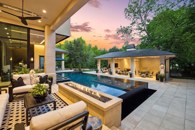 5214 Royal Ln, Dallas, TX 75229 - pool at dusk featuring an outdoor living space with a fire pit, ceiling fan, a patio area, and an outdoor pool