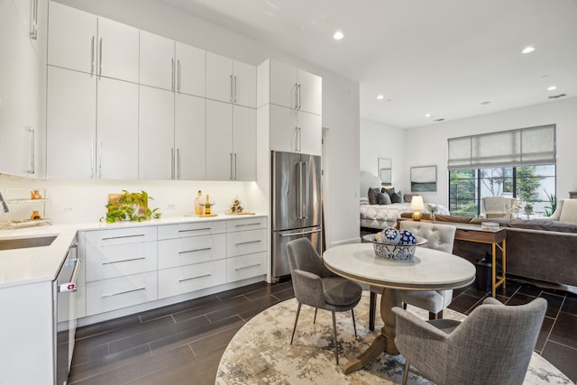 5214 Royal Ln, Dallas, TX 75229 - kitchen featuring appliances with stainless steel finishes, open floor plan, light countertops, a sink, and recessed lighting