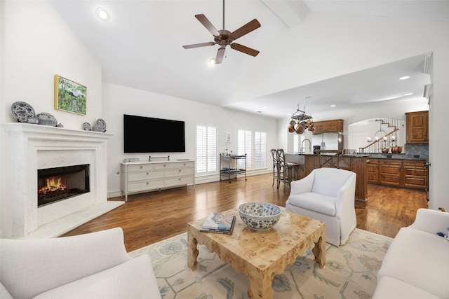 6137 Oram St, Dallas, TX 75214 - living room featuring a premium fireplace, a ceiling fan, wood finished floors, beamed ceiling, and arched walkways