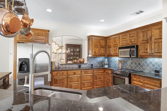 6137 Oram St, Dallas, TX 75214 - kitchen with stainless steel appliances, a sink, crown molding, decorative backsplash, and brown cabinets