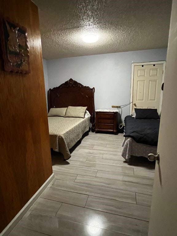 bedroom featuring a textured ceiling and wood tiled floors