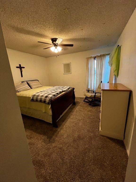 bedroom featuring a textured ceiling, dark carpet, and a ceiling fan