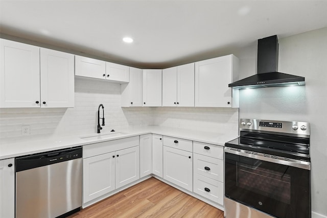 1220 Brittany Ln, Arlington, TX 76013 - kitchen featuring stainless steel appliances, wall chimney exhaust hood, a sink, light countertops, and white cabinets