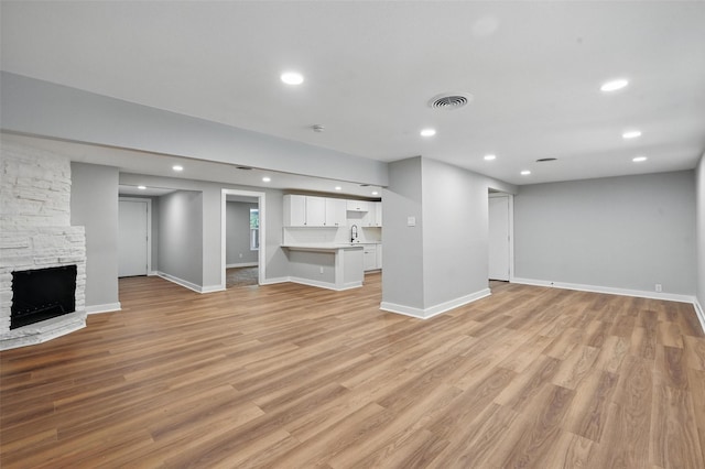1220 Brittany Ln, Arlington, TX 76013 - unfurnished living room featuring recessed lighting, a fireplace, light wood-style floors, baseboards, and a sink