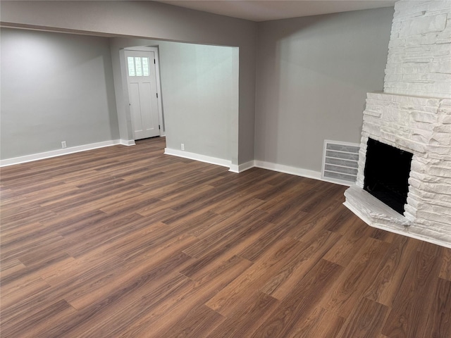 1220 Brittany Ln, Arlington, TX 76013 - unfurnished living room with baseboards, a stone fireplace, and dark wood-style floors