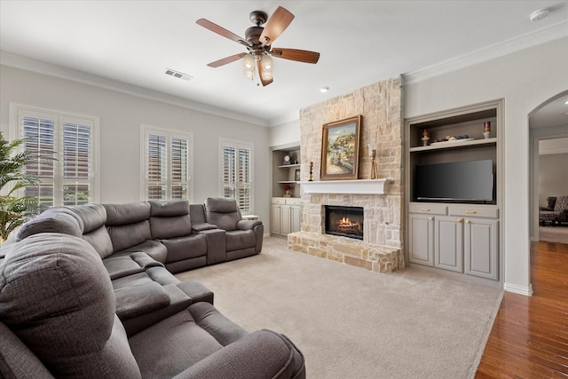 227 Justin Rd, Murphy, TX 75094 - living room featuring arched walkways, ornamental molding, built in shelves, ceiling fan, and a stone fireplace