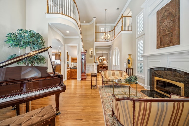 4024 Oakmeadow Dr, Plano, TX 75093 - sitting room featuring a towering ceiling, light wood-style flooring, ornamental molding, a chandelier, and a fireplace