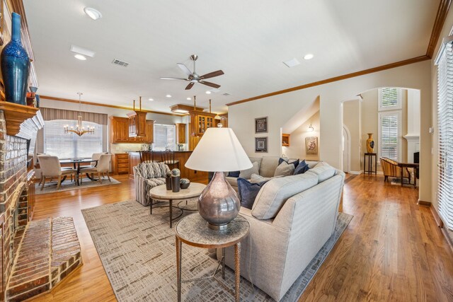 4024 Oakmeadow Dr, Plano, TX 75093 - living room featuring ceiling fan, a chandelier, ornamental molding, light wood finished floors, and arched walkways
