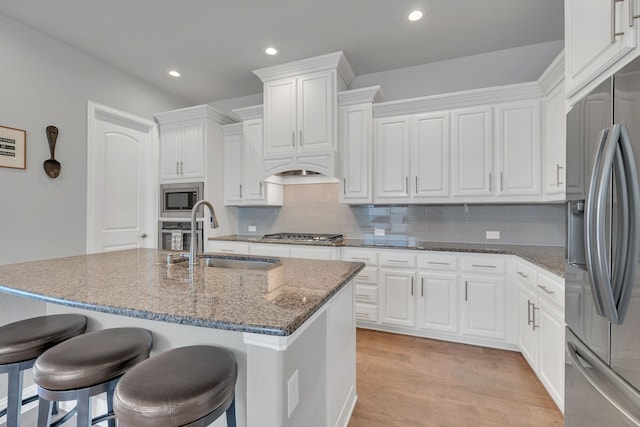 14937 Belclaire Ave, Aledo, TX 76008 - kitchen with stainless steel appliances, a sink, dark stone countertops, a kitchen bar, and light wood-type flooring