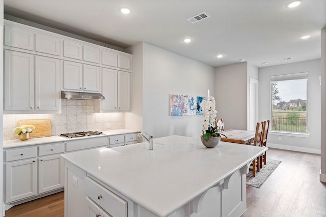 762 Corner Post Path, Celina, TX 75009 - kitchen with under cabinet range hood, stainless steel gas stovetop, a sink, light wood-type flooring, and tasteful backsplash